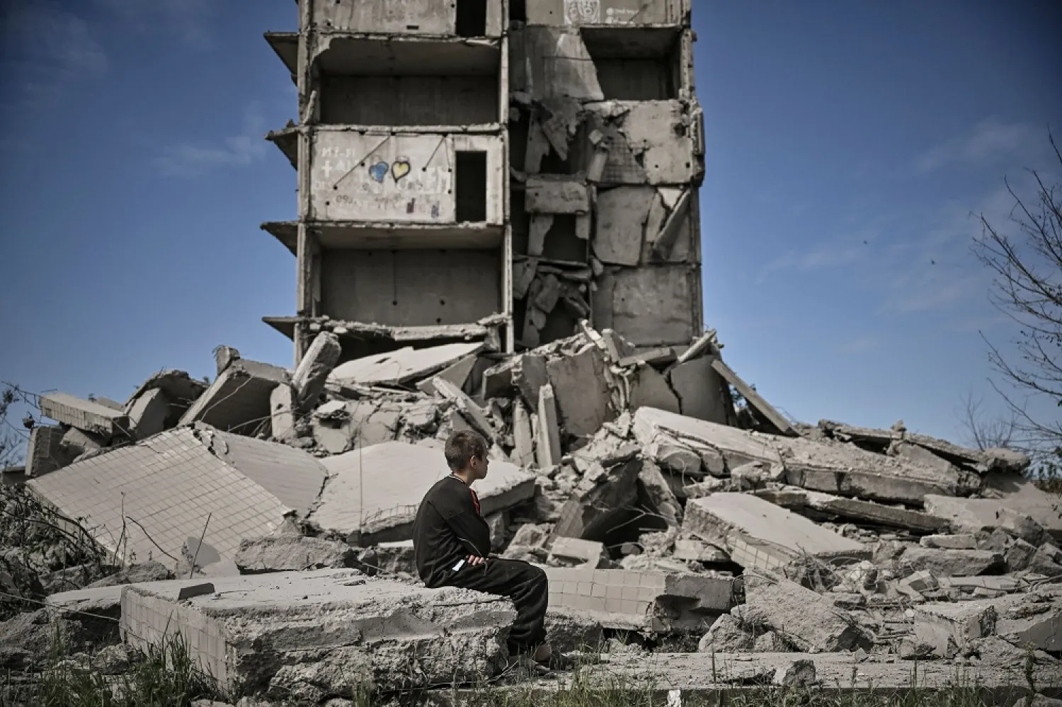 A young boy sits in front of a damaged building after a strike in Kramatorsk in the eastern Ukranian region of Donbas, on May 25, 2022. (AFP)