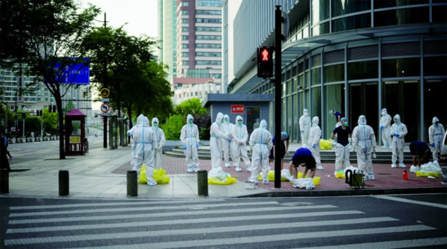 عمال صحيون في أحد شوارع شنغهاي الصينية (رويترز)