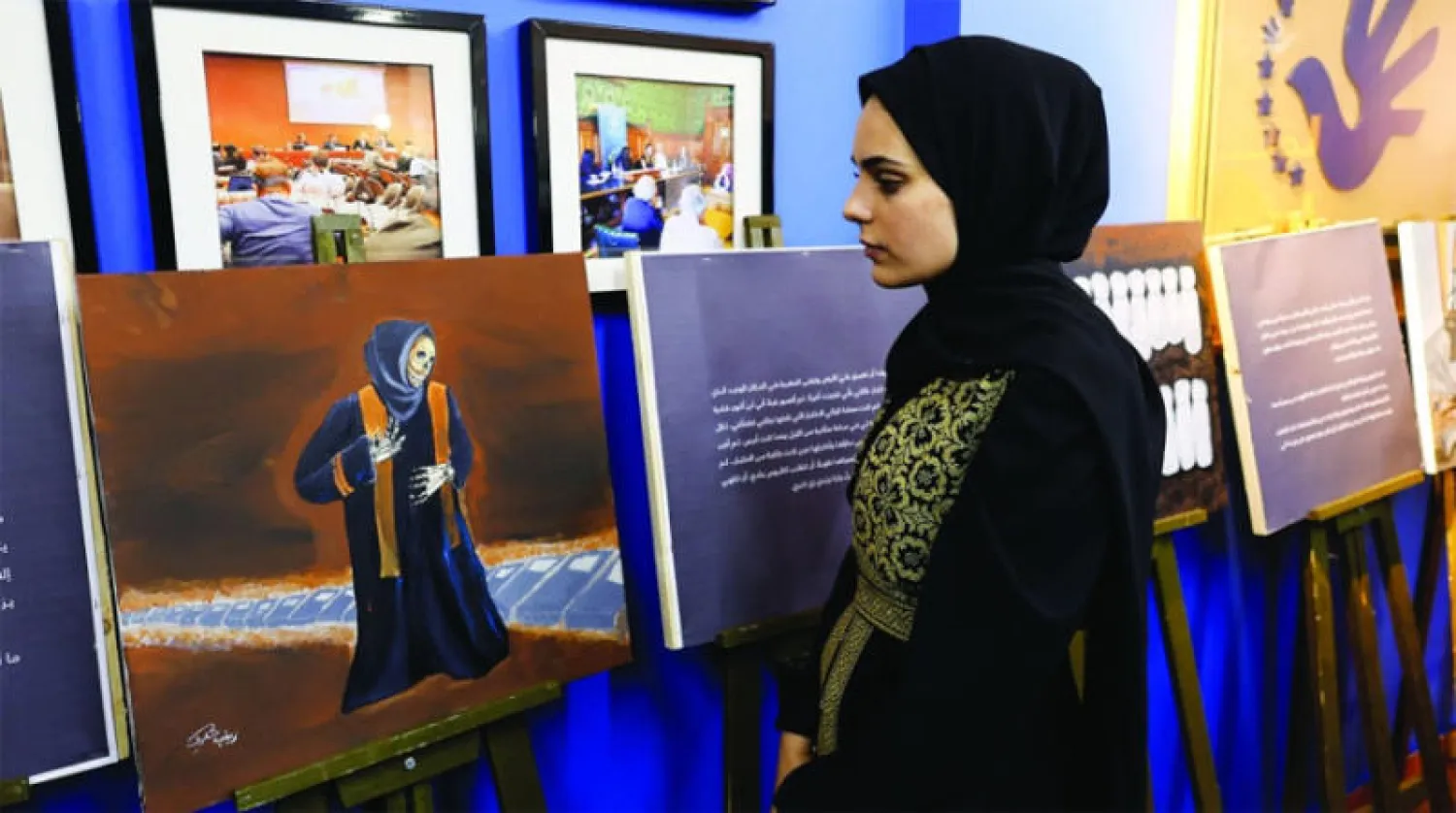 الفنانة زينب القولق تعرض لوحاتها في غزة (رويترز)