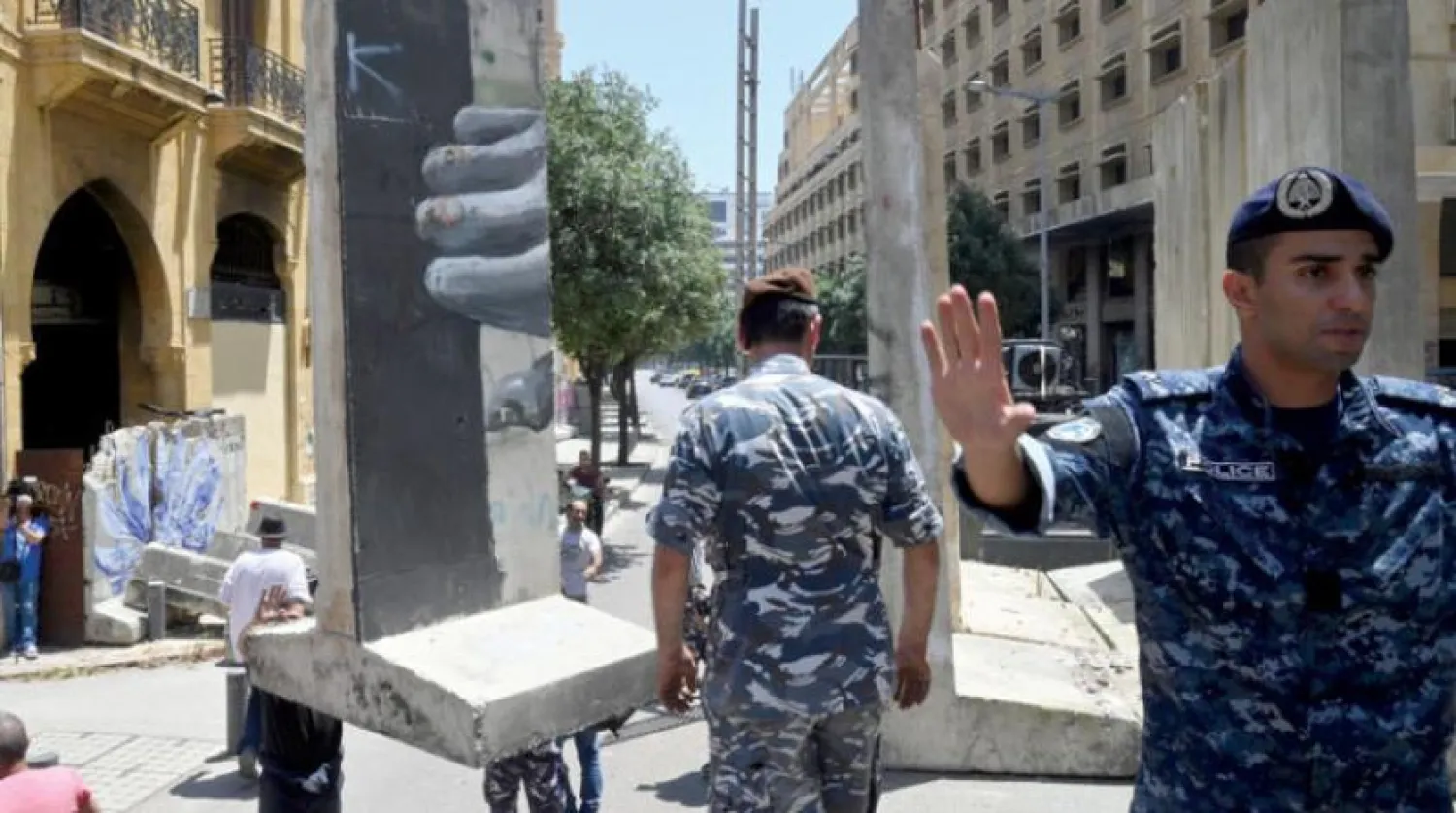 دو سیکورٹی اہلکار لبنانی پارلیمنٹ کے ہیڈ کوارٹر کی سڑکوں پر سیمنٹ کی رکاوٹ ہٹاتے ہوئے دیکھے جا سکتے ہیں (ای پی اے)