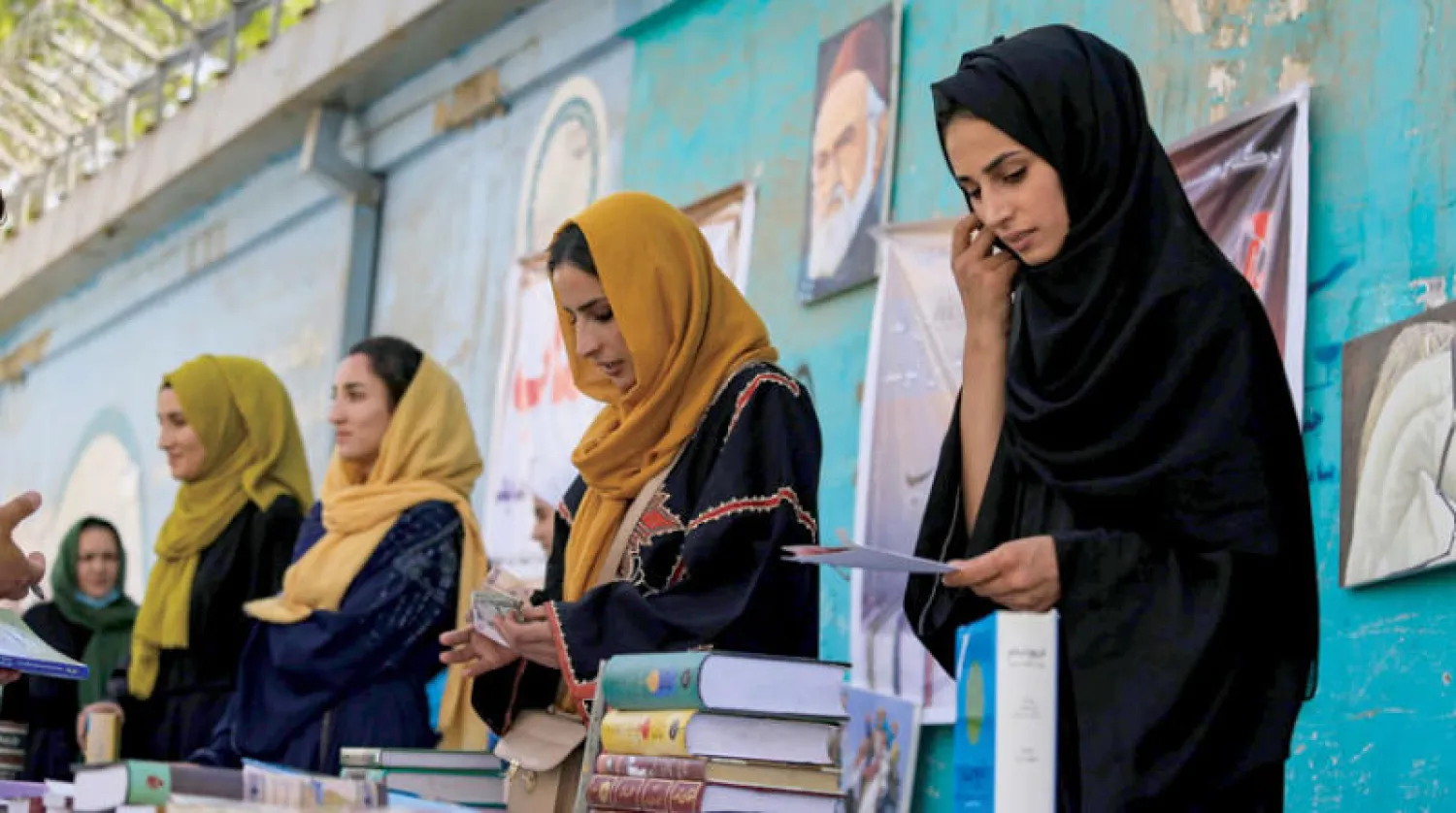 سيدات أفغانيات يتصفحن كتباً في أحد شوارع كابل 25 مايو (إ.ب.أ)