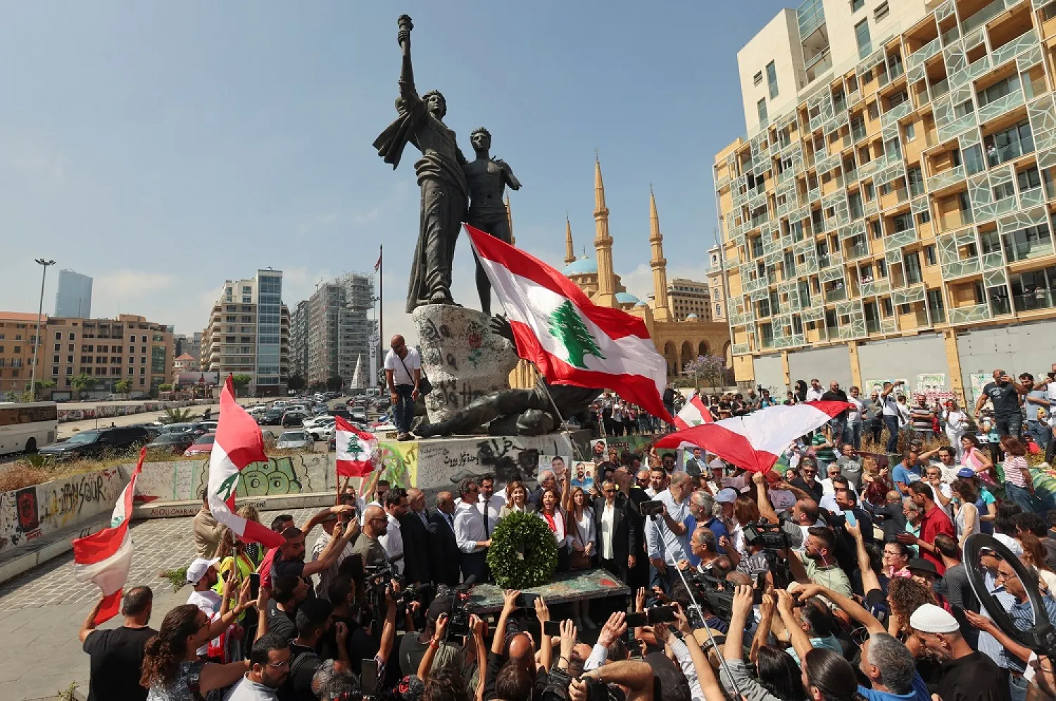 People hold Lebanese flags as newly-elected Lebanese lawmakers stand together at Martyrs' Square before the Lebanese parliament convenes for the first session post-election where they are expected to elect speaker and deputy speaker, in Beirut, Lebanon May 31, 2022. (Reuters)