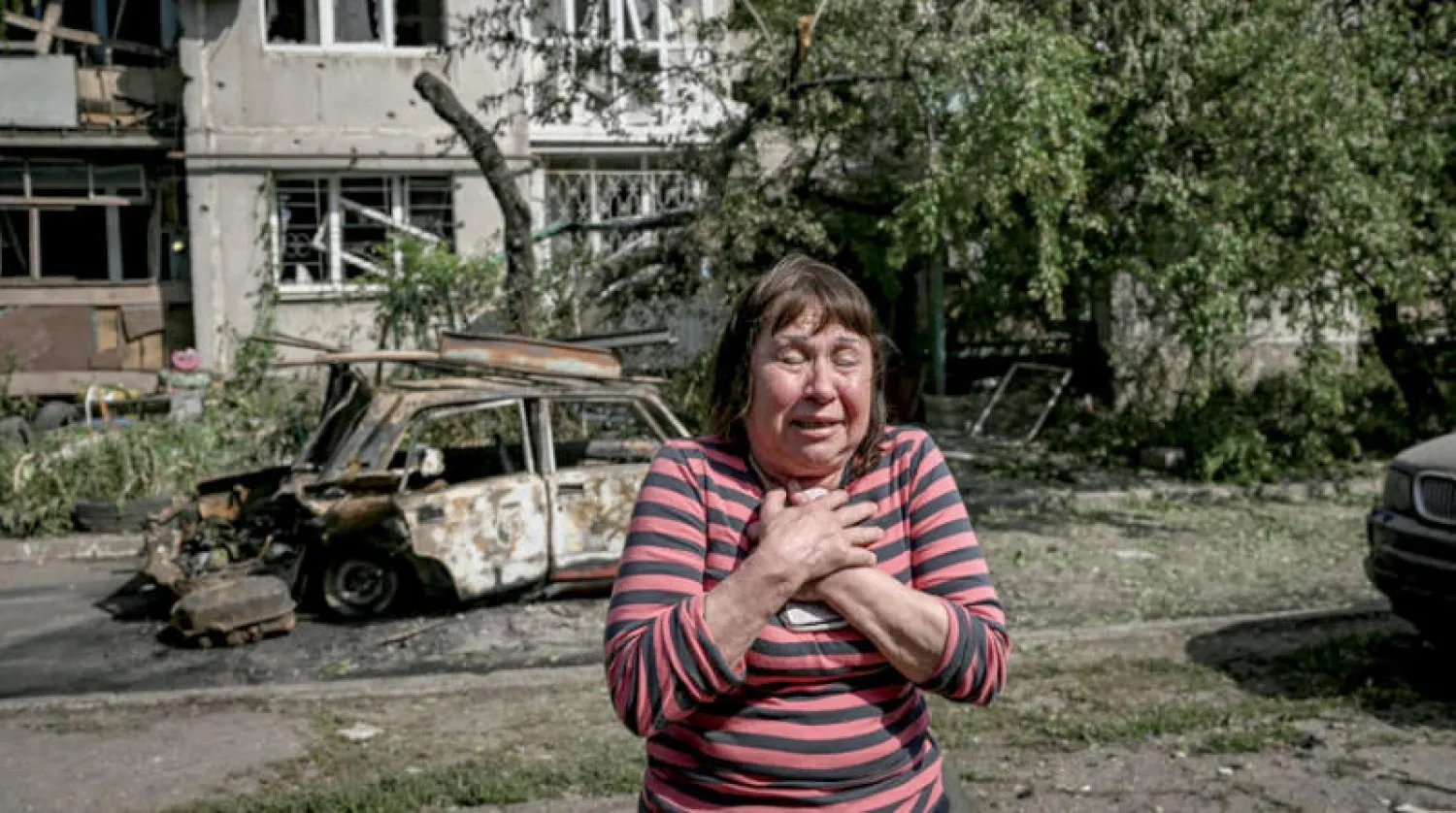 امرأة أمام مبنى سكني أُصيب بأضرار خلال قصف على مدينة سلوفيانسك بشرق أوكرنيا أمس (أ.ف.ب)
