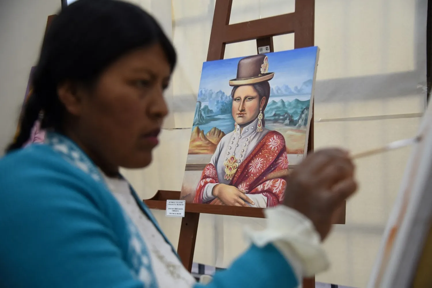 Claudia Callizaya, 32, a Bolivian painter known as Claudina, works on cholita-style Mona Lisa painting, at the El Alto Public University, in El Alto, Bolivia May 21, 2022. Picture taken May 21, 2022. (Reuters)