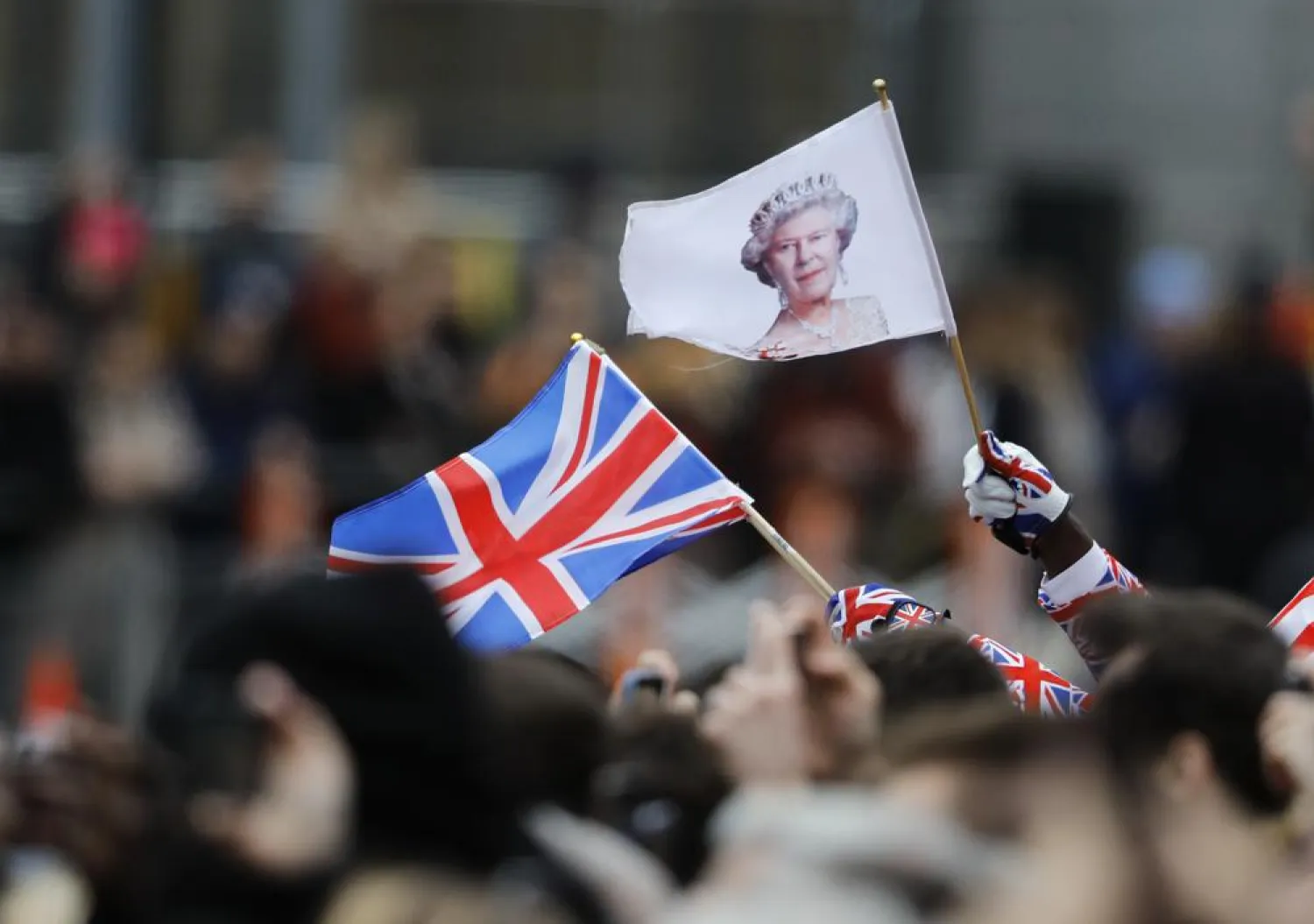 FILE - A man waves a British union flag and a flag bearing the image of Britain's Queen Elizabeth II ahead of the annual Commonwealth Day service at Westminster Abbey in London, Monday, March 9, 2020. (AP Photo/Frank Augstein, File)