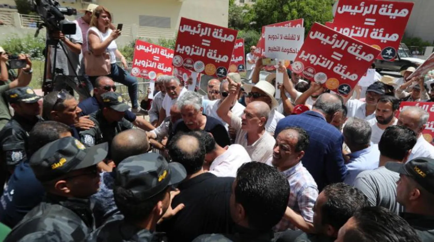 Tunus Cumhurbaşkanı Kays Said'e karşı düzenlenen gösterilerde protestocular, Bağımsız Yüksek Seçim Kurulu karargahına girmeye çalışırken güvenlik bariyerlerini aşmaya çalışıyor (EPA)