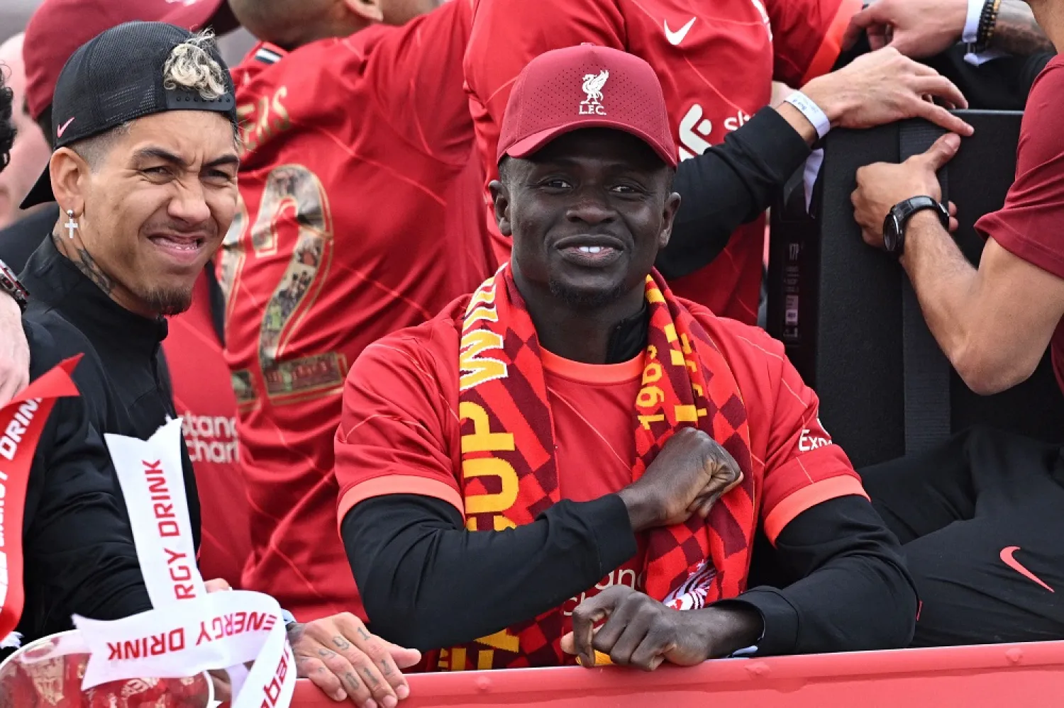 Liverpool's Brazilian striker Roberto Firmino (L) and Liverpool's Senegalese striker Sadio Mane celebrate from an open-top bus during a parade through the streets of Liverpool in north-west England on May 29, 2022, after winning the 2021-22 League Cup and FA Cup. (AFP)
