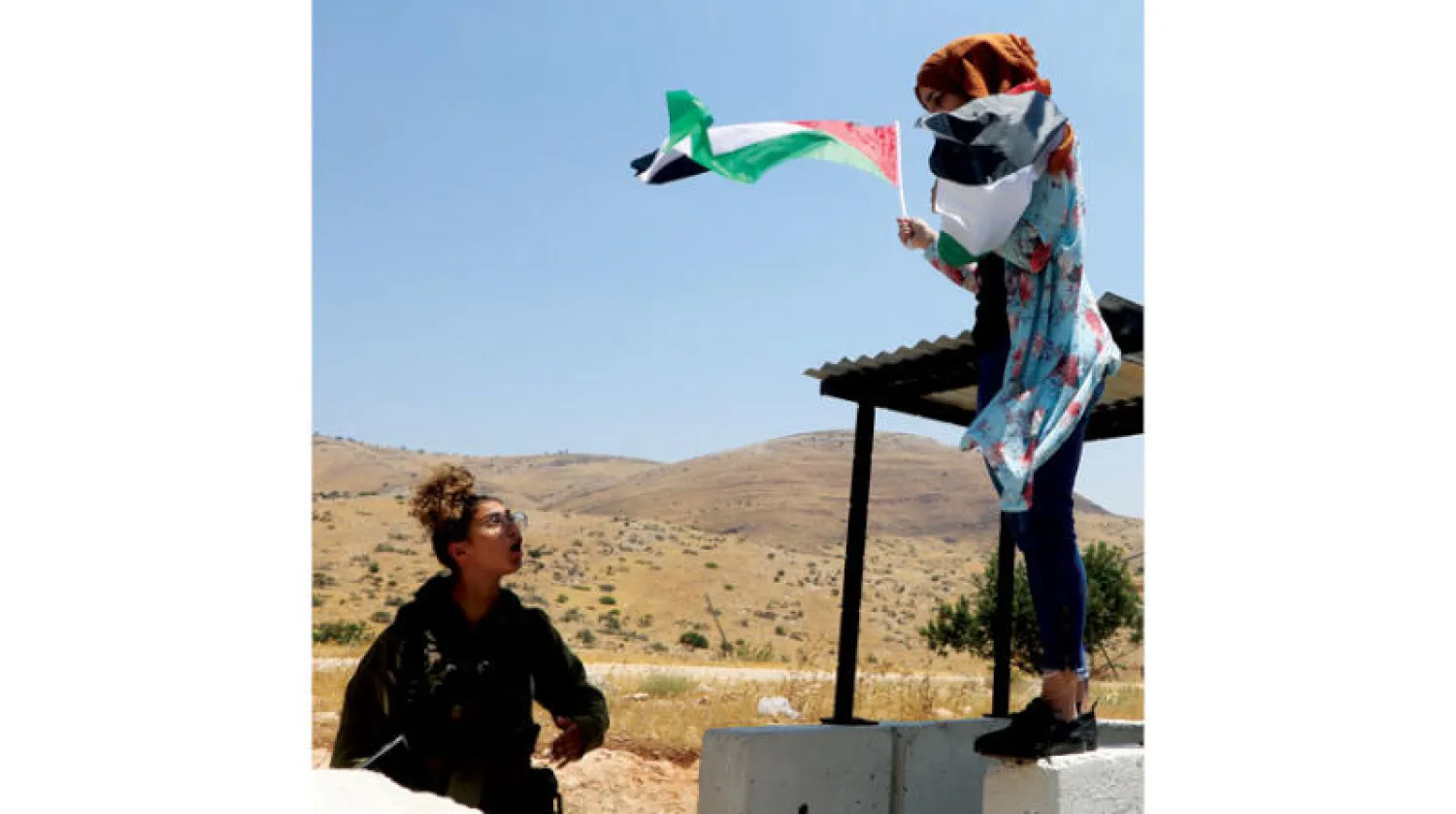 جندية إسرائيلية تتجادل مع فلسطينية خلال احتجاج على المستوطنات بالقرب من طوباس بالضفة أمس (إ.ب.أ)