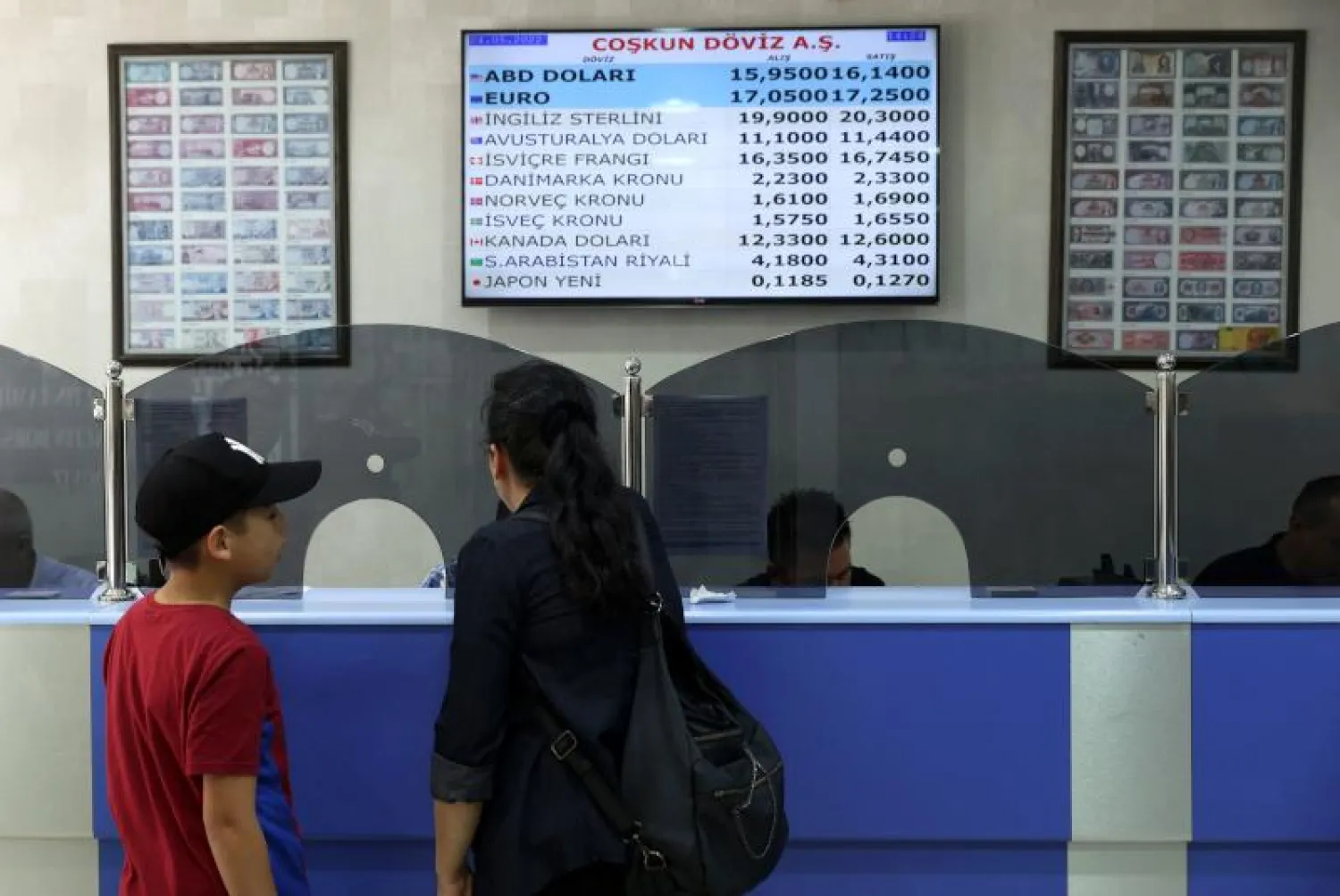 أشخاص يتبادلون الأموال بمكتب صرافة في أنقرة (أ.ف.ب)
