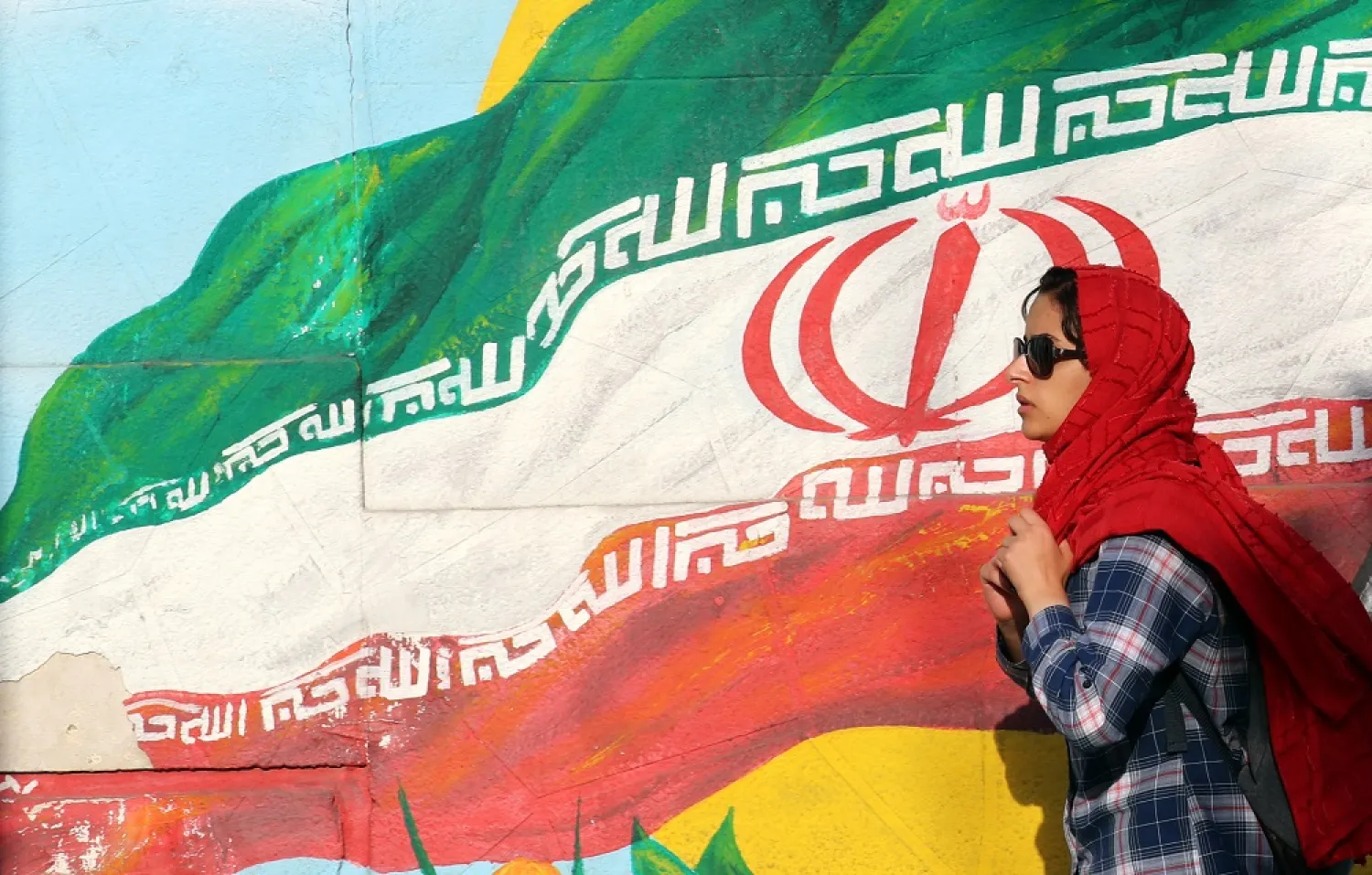 An Iranian walks next to a wall painting of Iran’s national flag at a street in Tehran, Iran, 02 June 2022. (EPA)