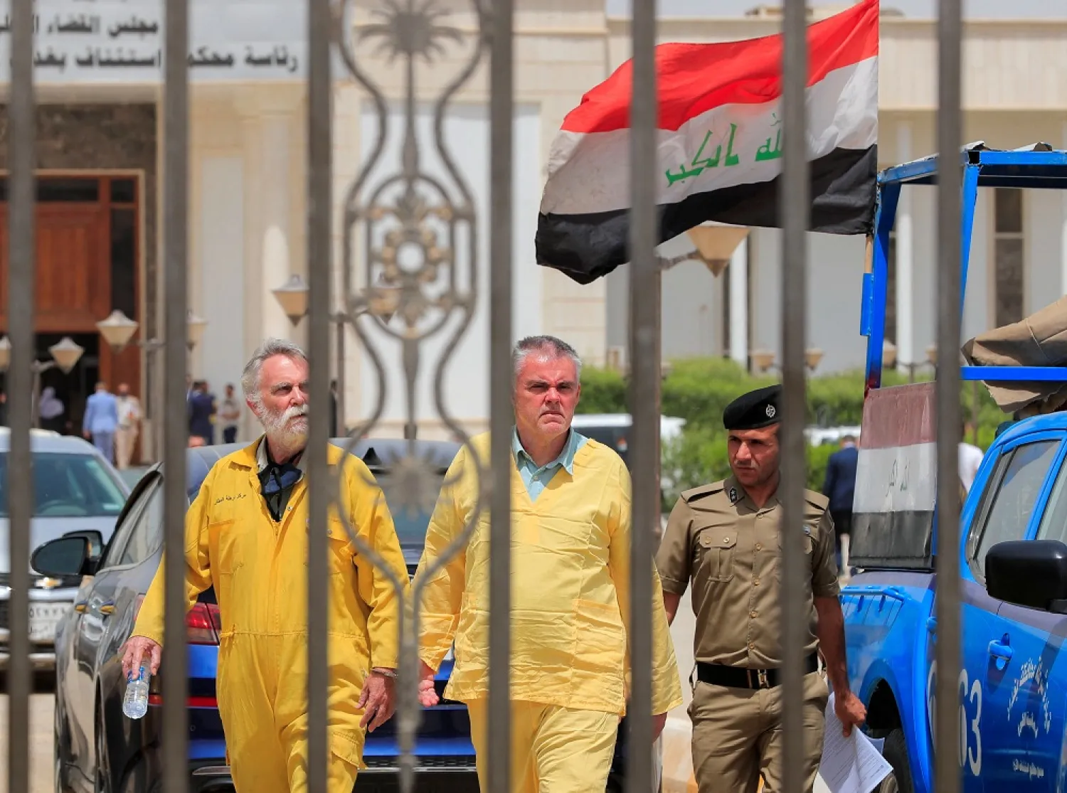 Iraqi policemen escort Jim Fitton from Britain and Volker Waldmann from Germany in handcuffs, who are suspected of smuggling ancient artifacts out of Iraq, outside a court in Baghdad, Iraq, May 22, 2022. (Reuters)