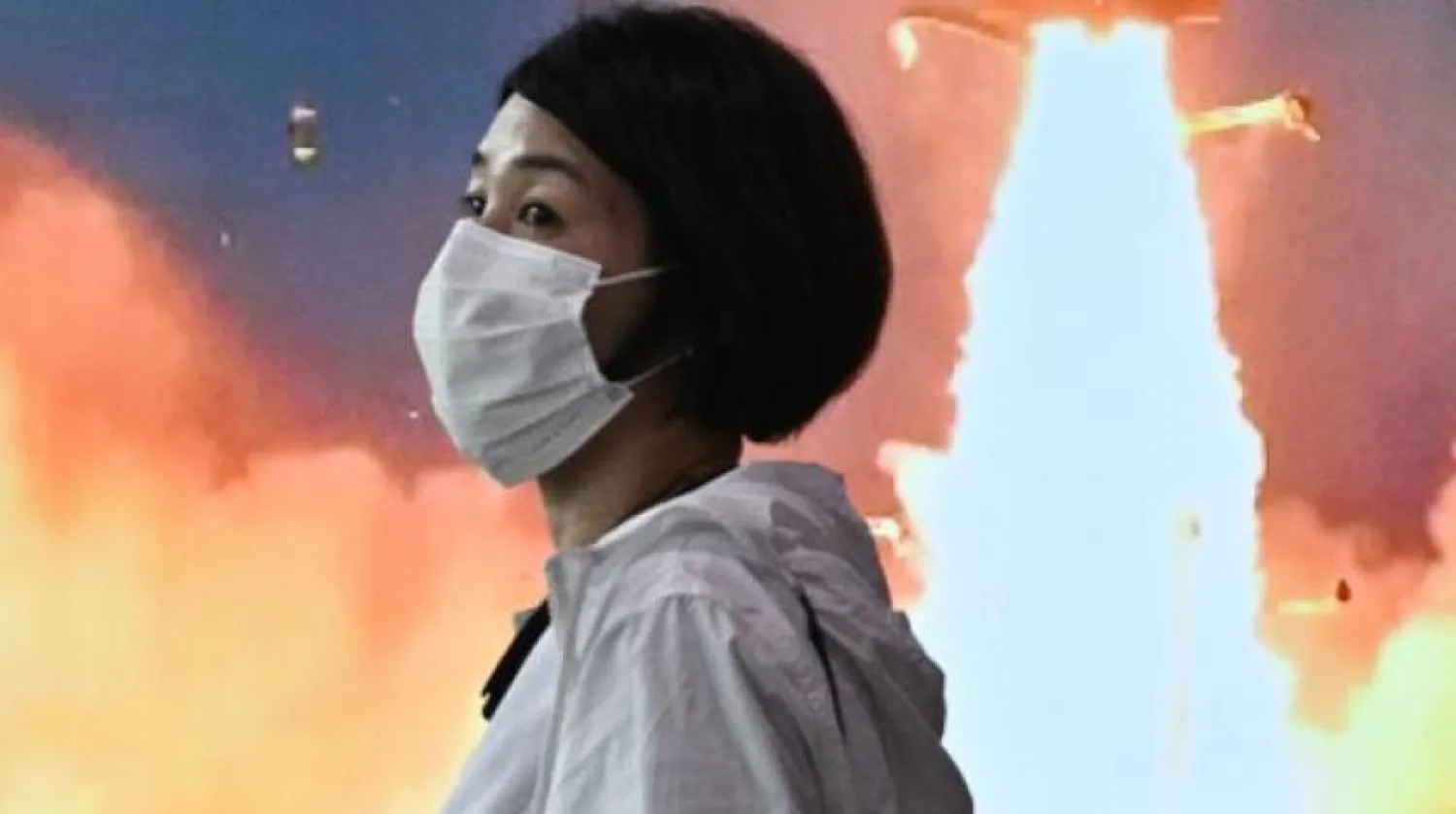 Seul'de Kuzey Kore'nin füze fırlatma fotoğraflarını gösteren bir ekranın önünden geçen bir kadın (AFP)
