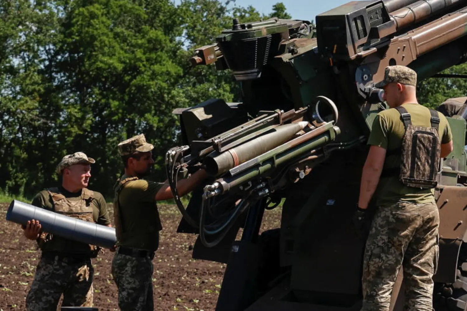 جنود أوكرانيون يقومون بتحميل قذيفة قبل إطلاقها باتجاه أحد المواقع الروسية في منطقة دونيتسك (رويترز)