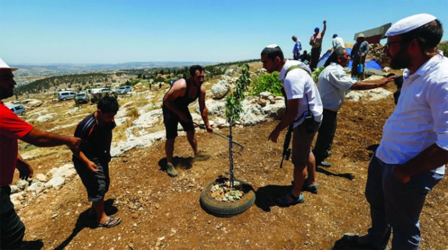 مستوطنون يطلبون من فلسطينيين إخلاء المكان خلال احتجاج على النشاط الاستيطاني قرب الخليل (رويترز)