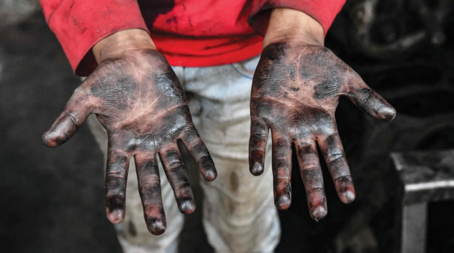 فتى سوري يعمل بتصليح السيارات يُظهر يديه في ريف حلب شمال البلاد في 11 الشهر الجاري (أ.ف.ب)