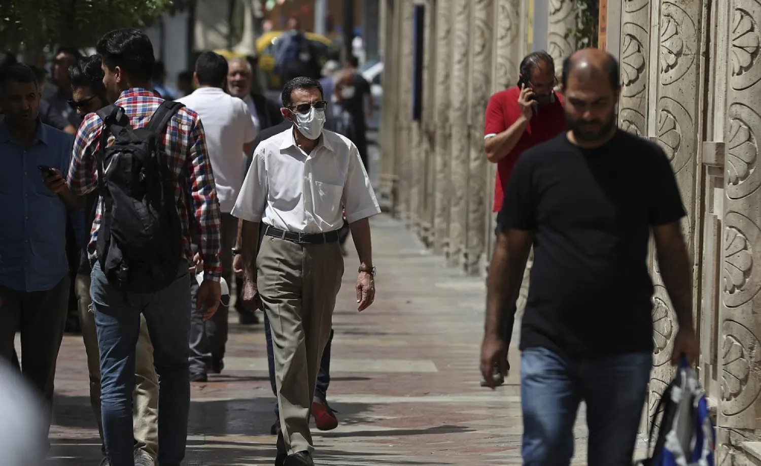 People walk on the sidewalk in Ferdowsi Street, Tehran, Iran, Sunday, June 12, 2022. (AP)