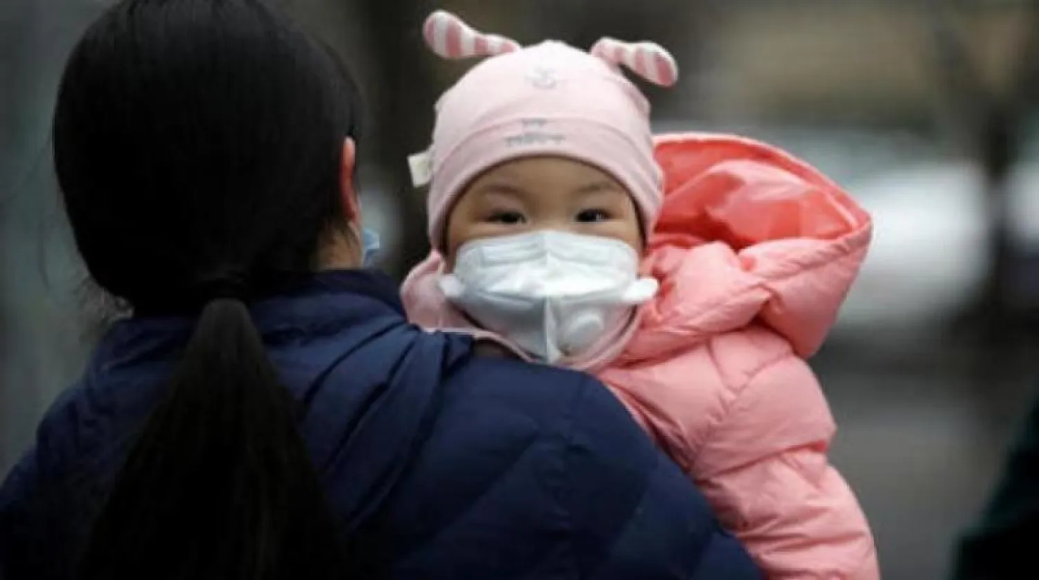 طفلة صينية ترتدي كمامة للوقاية من «كورونا» (رويترز)