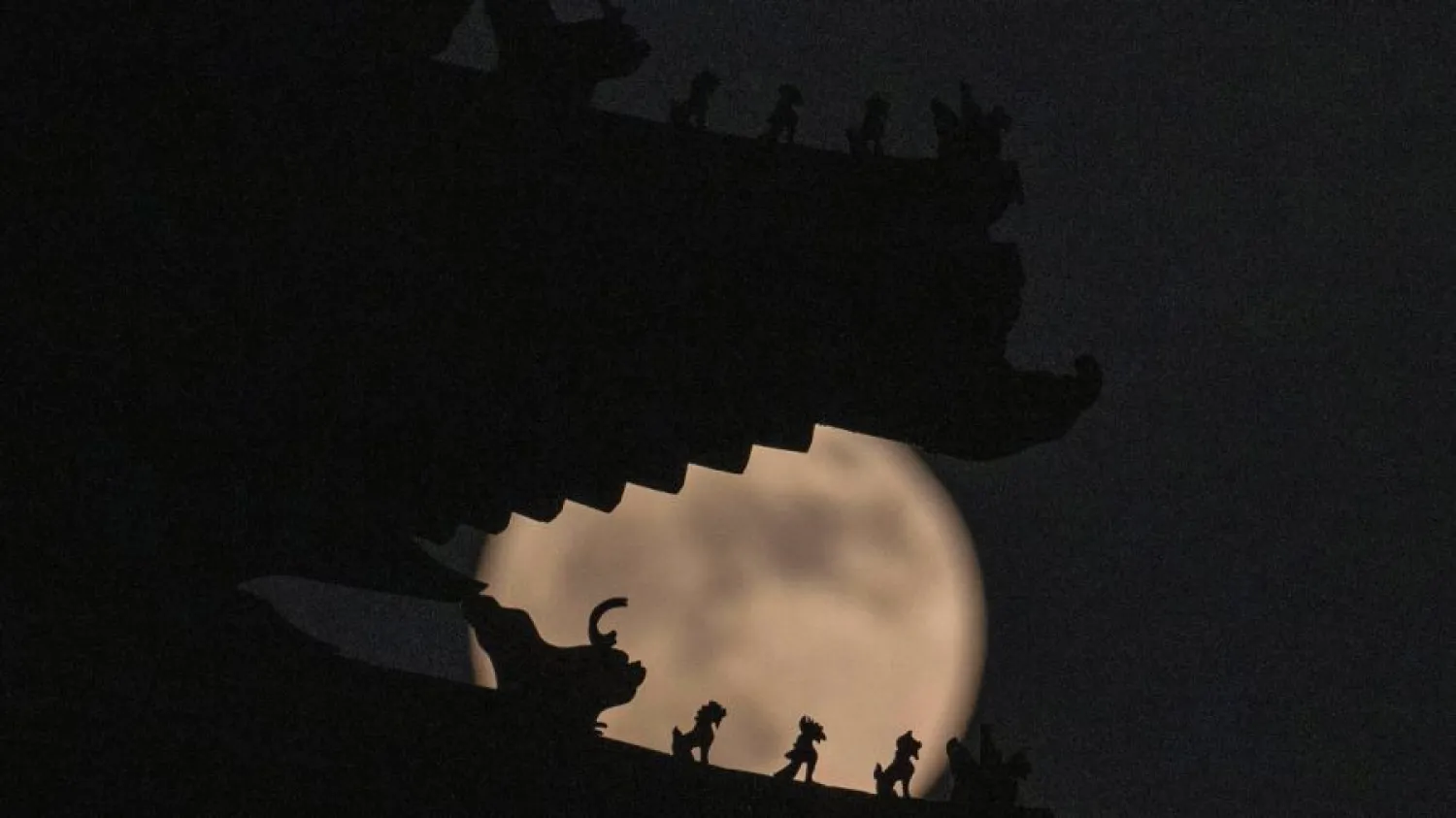 Roof decorations on the corner tower at the Forbidden City depicting sacred beasts are silhouetted against a supermoon, Tuesday, June 14, 2022, in Beijing. (AP Photo/Ng Han Guan)