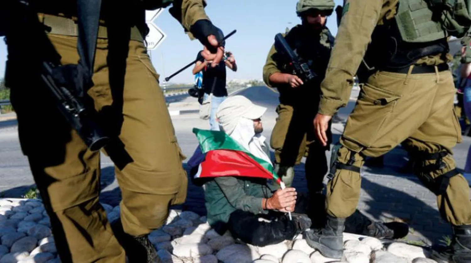 Askerler, Azzun köyünde yerleşimcilerin Filistin bayraklarını kaldırmasını engellemeye çalışan barış eylemcilerini tutukladı (EPA)