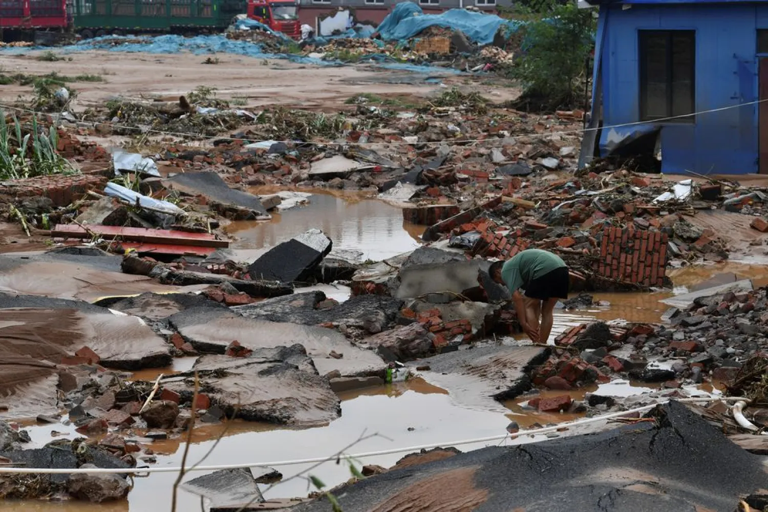 A resident is seen on a road damaged by floodwaters following heavy rainfall in Gongyi city, Henan province, China July 22, 2021. (Reuters)
