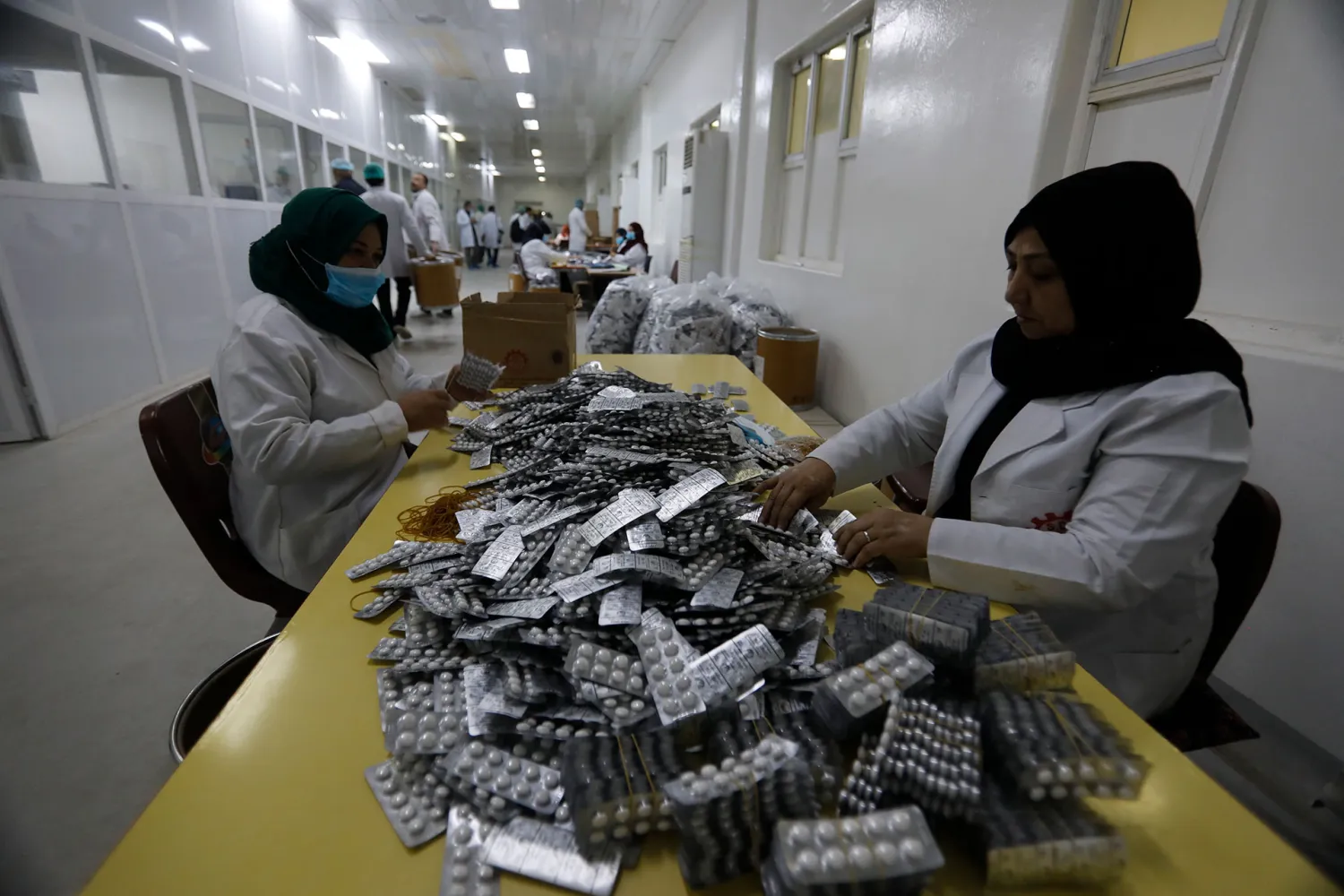 Workers manually box medicines at the State Company for Drugs Industries factory in Samara. REUTERS/Khalid al-Mousily