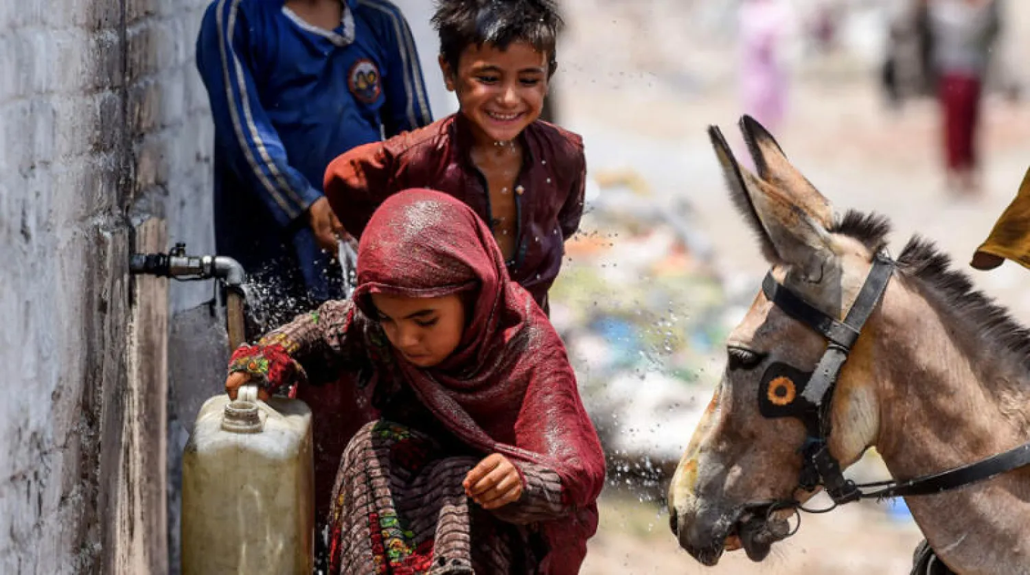أطفال من اللاجئين الأفغان يعيشون في باكستان يجلبون الماء من صنبور في ضواحي لاهور الأحد الماضي عشية «يوم اللاجئ العالمي» (أ.ف.ب)