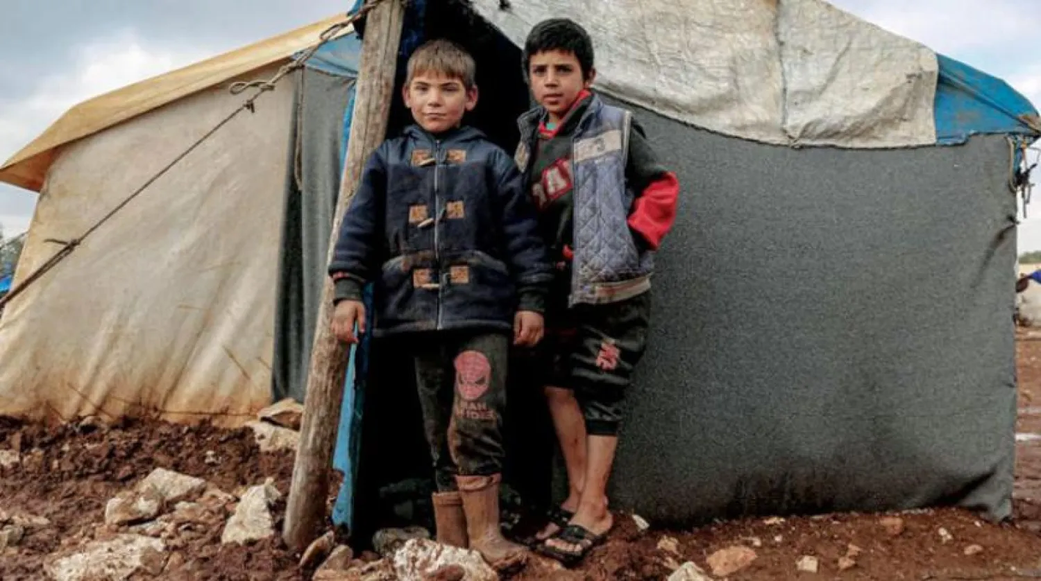 Two children of families displaced by the war in Syria outside their tent north of the country. (United Nations)
