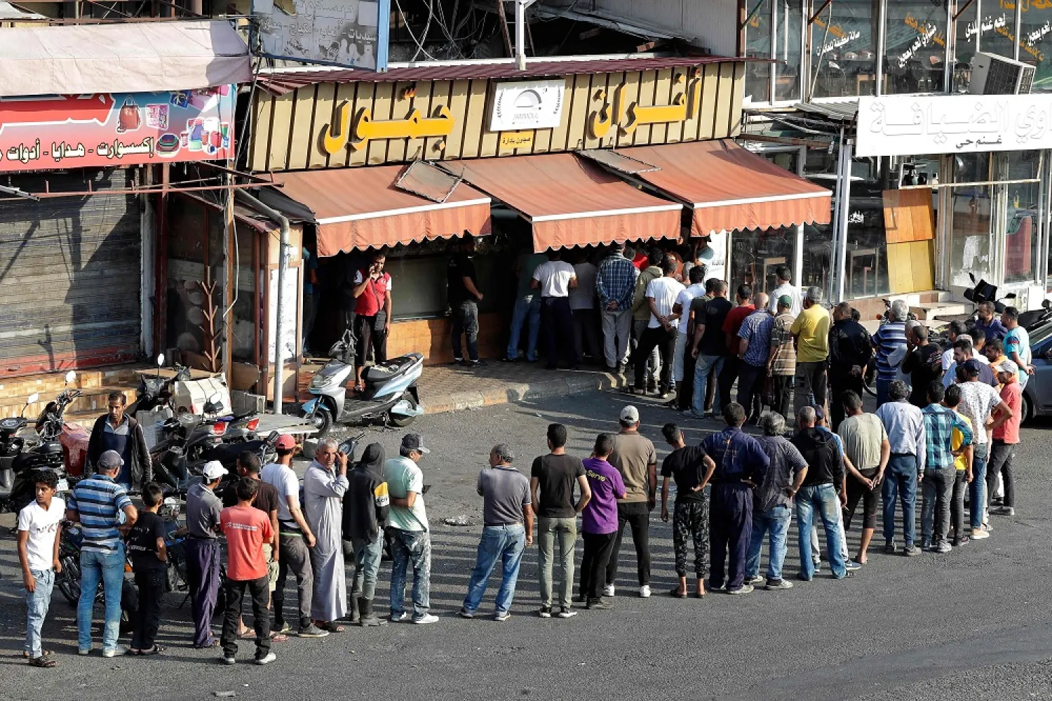 People line up in front of a bakery to buy bread in Lebanon's southern city of Sidon on June 22, 2022 as fuel and wheat shortage deepens. (AFP)
