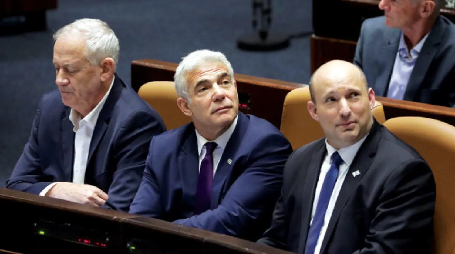 رئيس الوزراء الإسرائيلي مع الوزيرين لبيد وغانتس يتابعون التصويت في جلسة حل الكنيست أمس (إ.ب.أ)