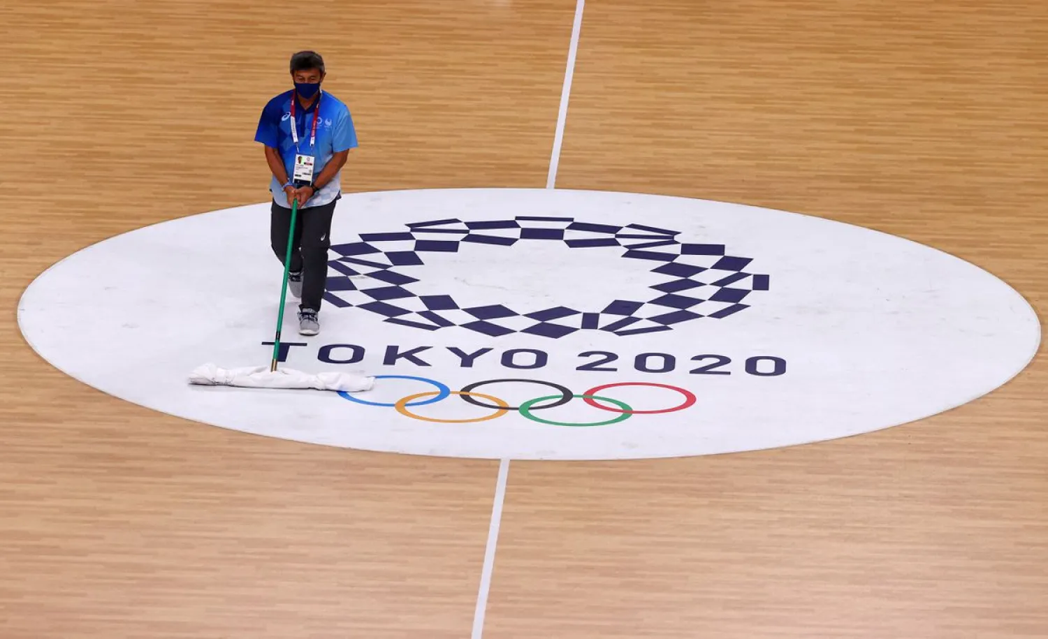 Tokyo 2020 Olympics - Handball - Women - Quarterfinal - Sweden v South Korea - Yoyogi National Stadium - Tokyo, Japan - August 4, 2021. A staff member cleans the floor over the Tokyo 2020 Olympics logo. (Reuters)