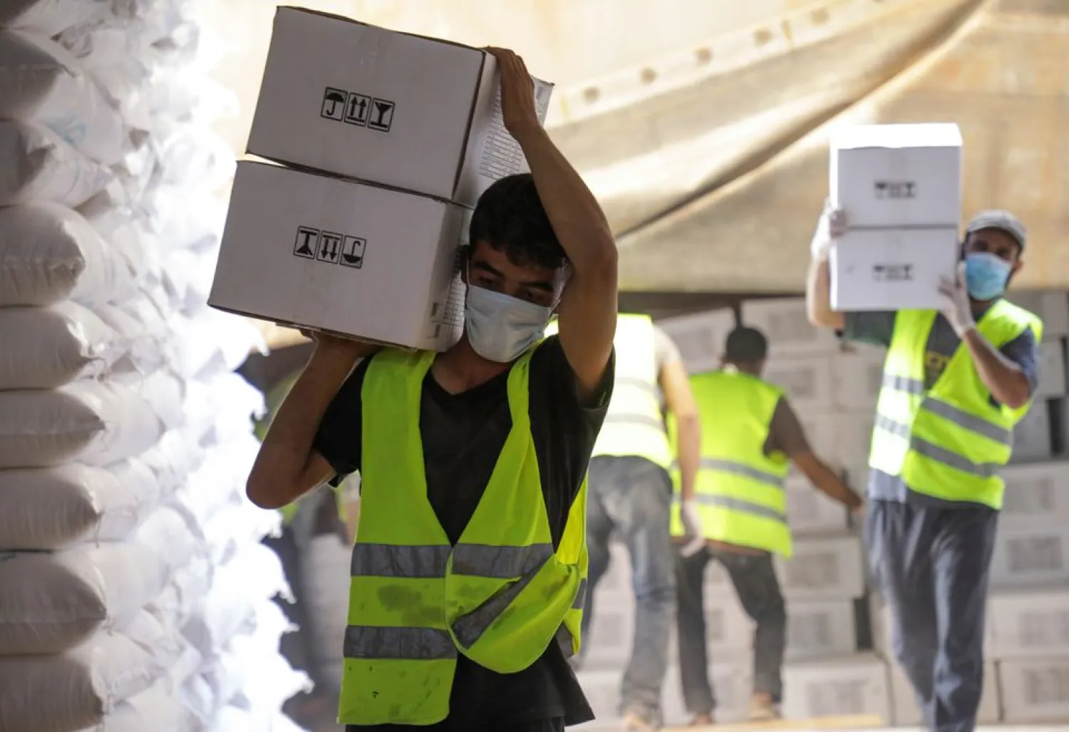Workers carry boxes of humanitarian aid near Bab al-Hawa crossing at the Syrian-Turkish border, in Idlib governorate, Syria, June 30, 2021. REUTERS/Mahmoud Hassano