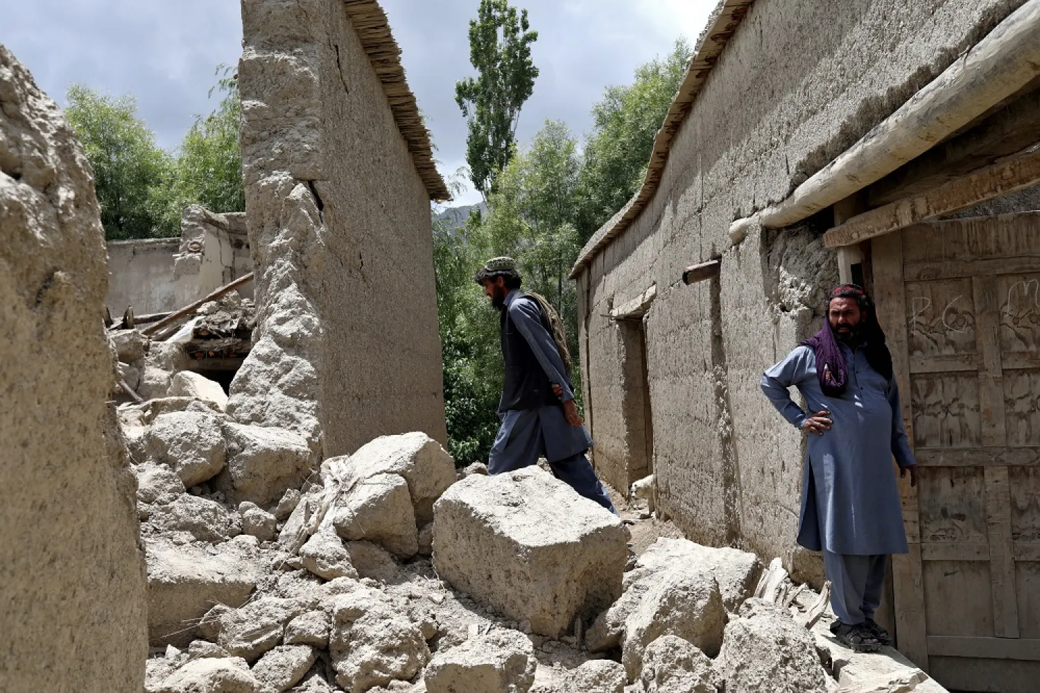 Afghan men stand on the debris of their house that was damaged by an earthquake in Gayan, Afghanistan, June 23, 2022. (Reuters)