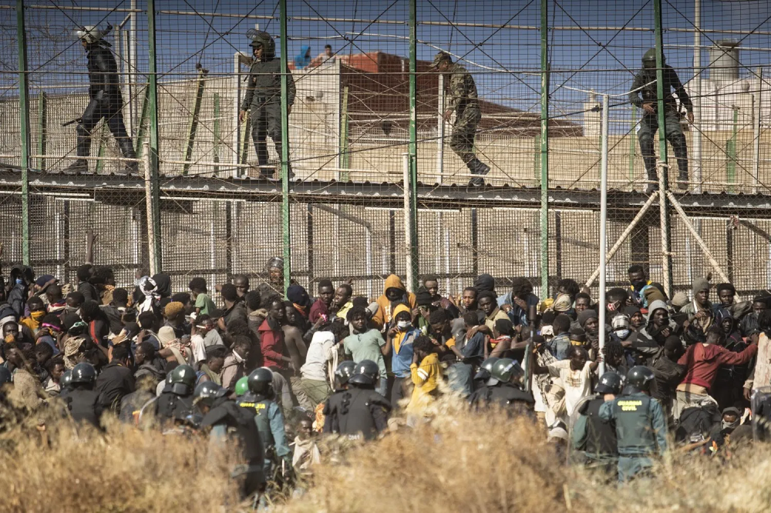 Riot police officers cordon off the area after migrants arrive on Spanish soil and crossing the fences separating the Spanish enclave of Melilla from Morocco in Melilla, Spain, Friday, June 24, 2022. (AP)