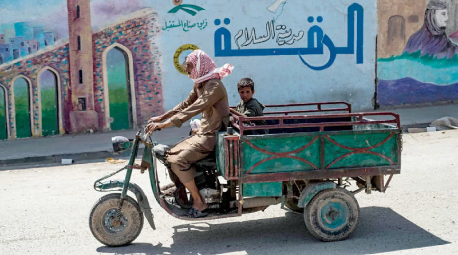 رجل وابنه يستقلان عربة في مدينة الرقة شمال سوريا في 19 يونيو الجاري (أ.ف.ب)