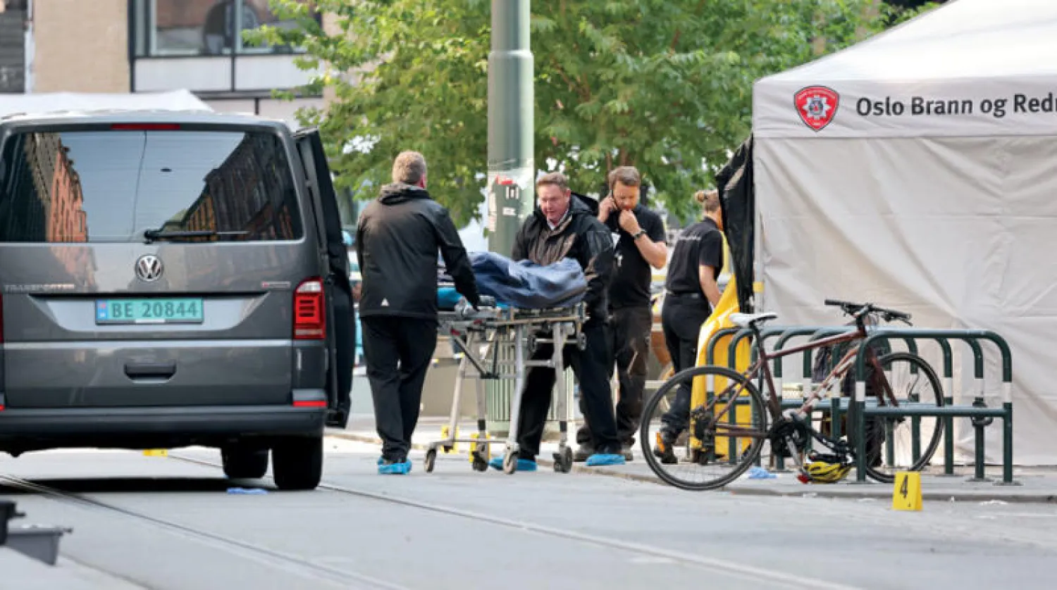 رجلا شرطة ينقلان جثة أحد القتلى من مكان إطلاق النار في وسط أوسلو (إ.ب.أ)