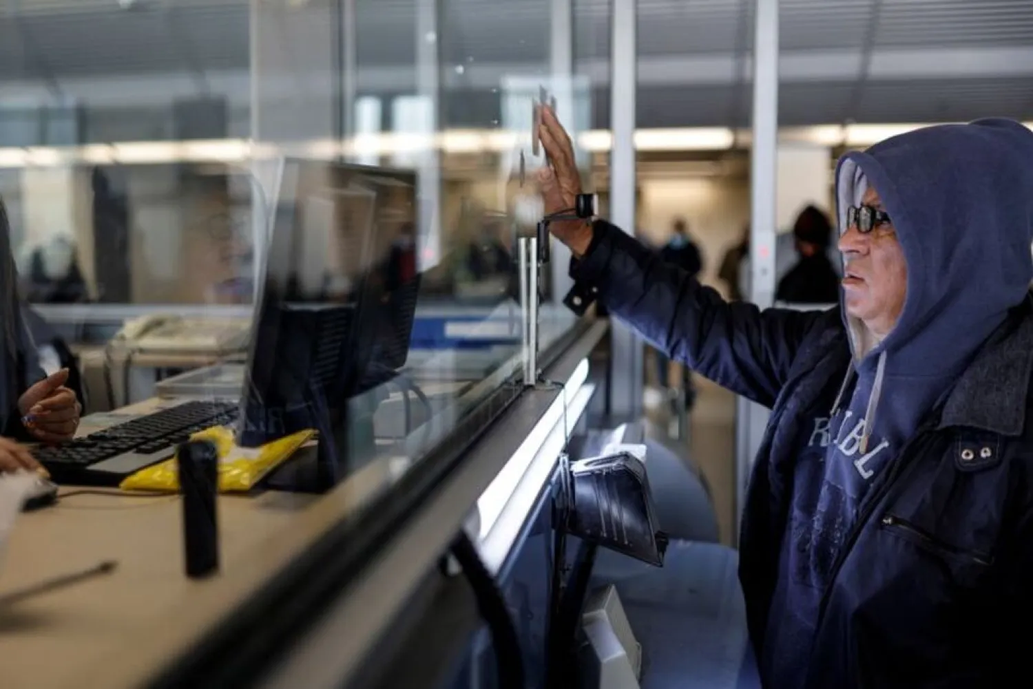 A Palestinian worker holds up his ID card as he is processed after entering Israel through the Erez Crossing, on the border with Gaza, February 20, 2022. (Reuters)