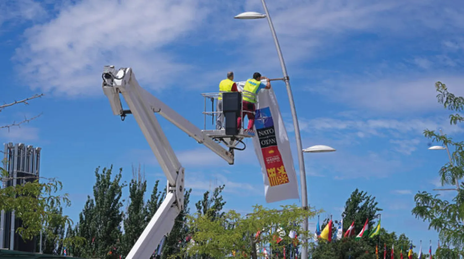 عمال يضعون لافتة لحلف «الناتو» في مدريد استعداداً للقمة (أ.ب)
