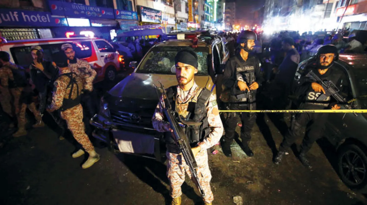 مسؤولون أمنيون باكستانيون يحرسون موقع تفجير إرهابي في كراتشي 12 مايو 2022 حيث قُتل شخص واحد وأصيب 12 (إ.ب.أ)