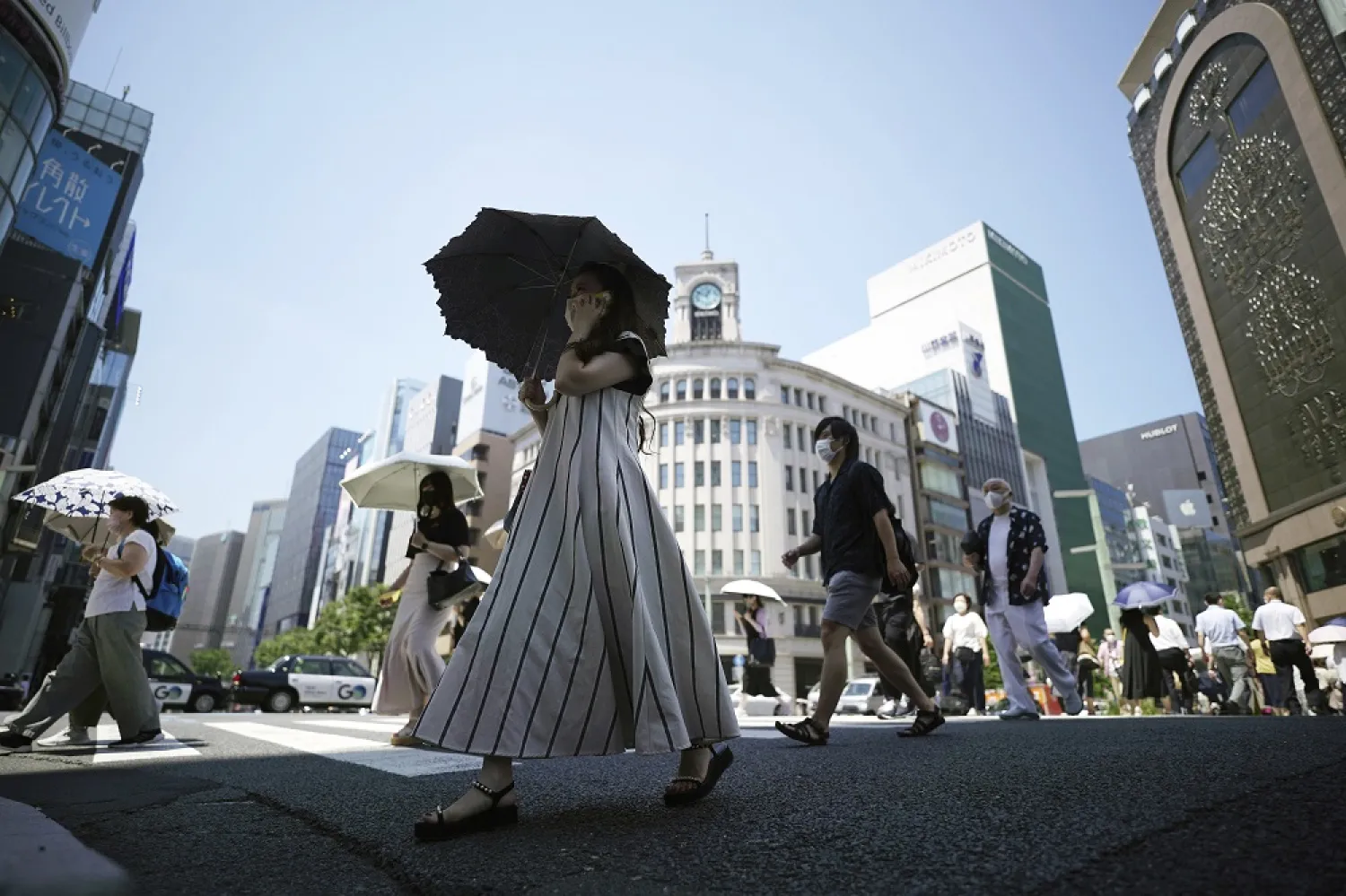 People walk over a pedestrian crossing under an intense sun Tuesday, June 28, 2022, in Tokyo. (AP)