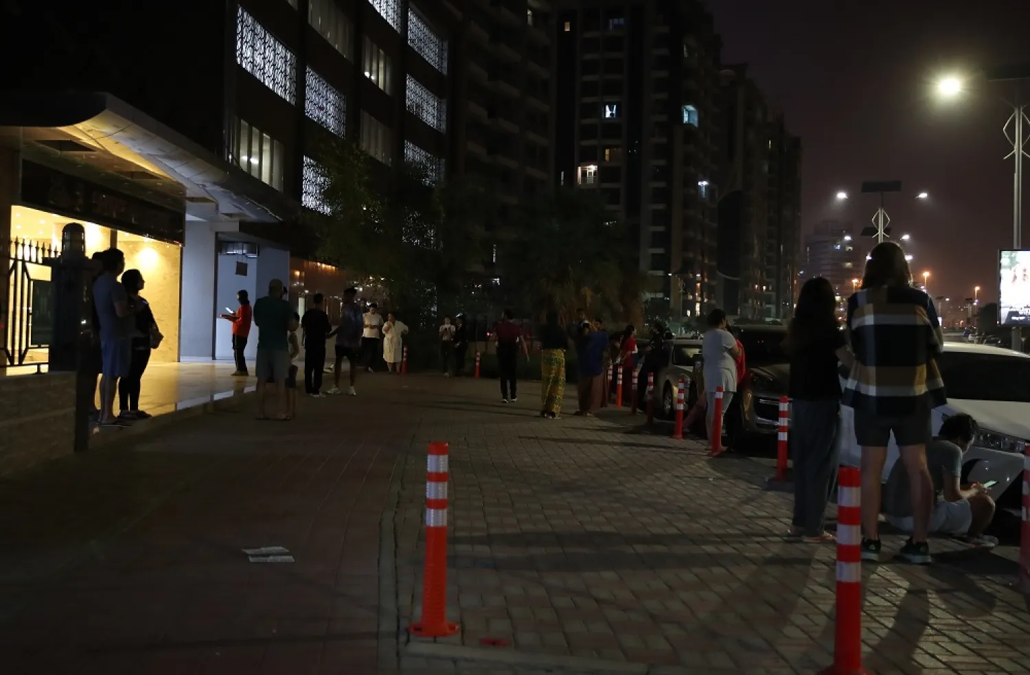 People gather in front of their residential building in the Gulf emirate of Dubai, United Arab Emirates, in the early hours of 02 July 2022. A recorded earthquake of magnitude 6.5 has hit southern Iran with tremors felt in Dubai, UAE. (EPA)