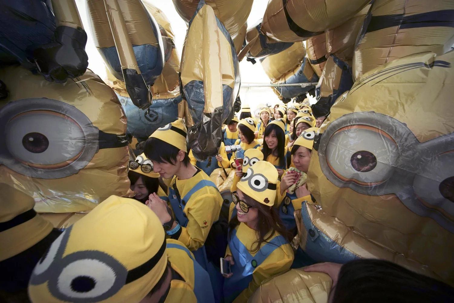FILE - Participants dressed as minion characters from the "Despicable Me" franchise walk through minion balloons during the Minions Run in Tokyo on Feb. 13, 2016. (AP Photo/Eugene Hoshiko, File)