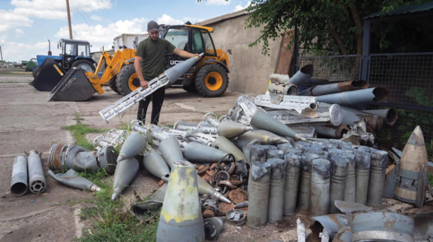 أوكراني يجمع بقايا صواريخ روسية وجدها في مزرعته قرب جبهة قتال في منطقة دنيبروبيتروفسك أمس (أ.ب)