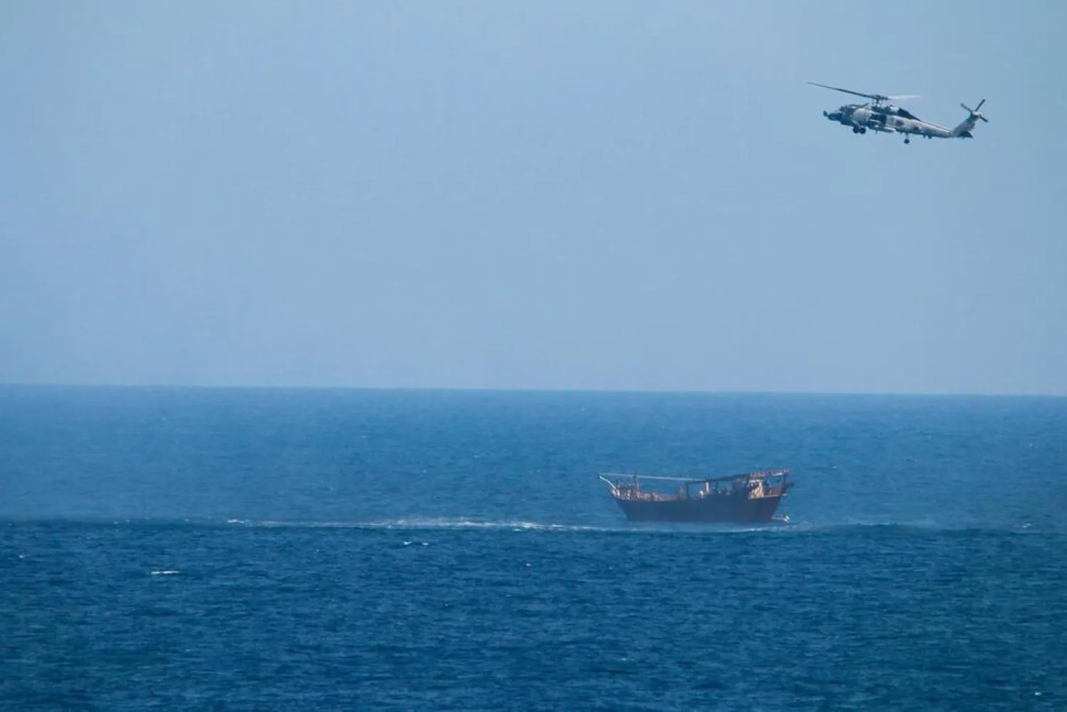 A US Navy Seahawk helicopter flies over a stateless dhow later found to be carrying a hidden arms shipment in the Arabian Sea, May 6, 2021. (US Navy via AP)