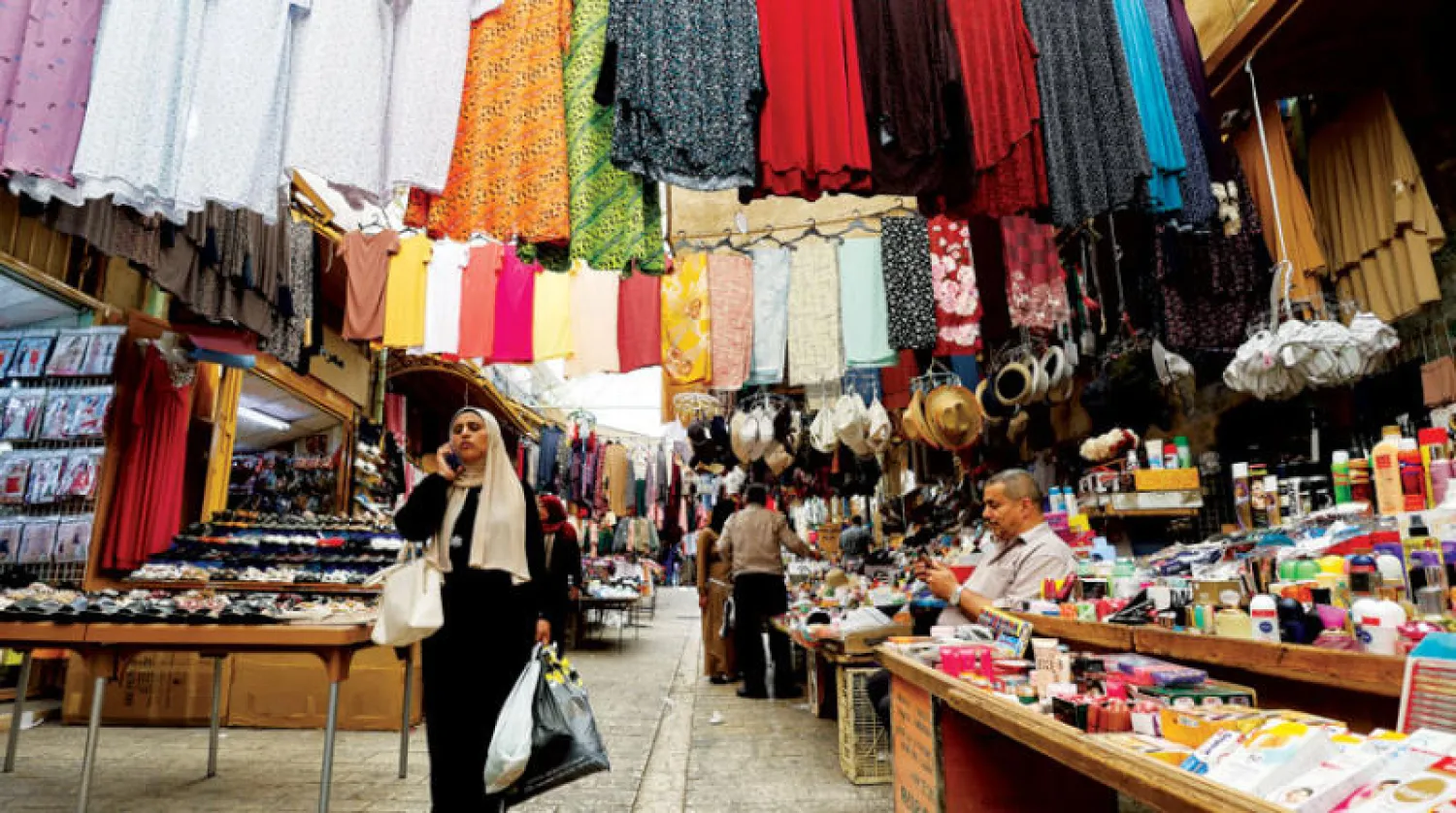 فلسطينية تحمل أكياس تسوق لعيد الأضحى في البلدة القديمة بالخليل بالضفة (رويترز)