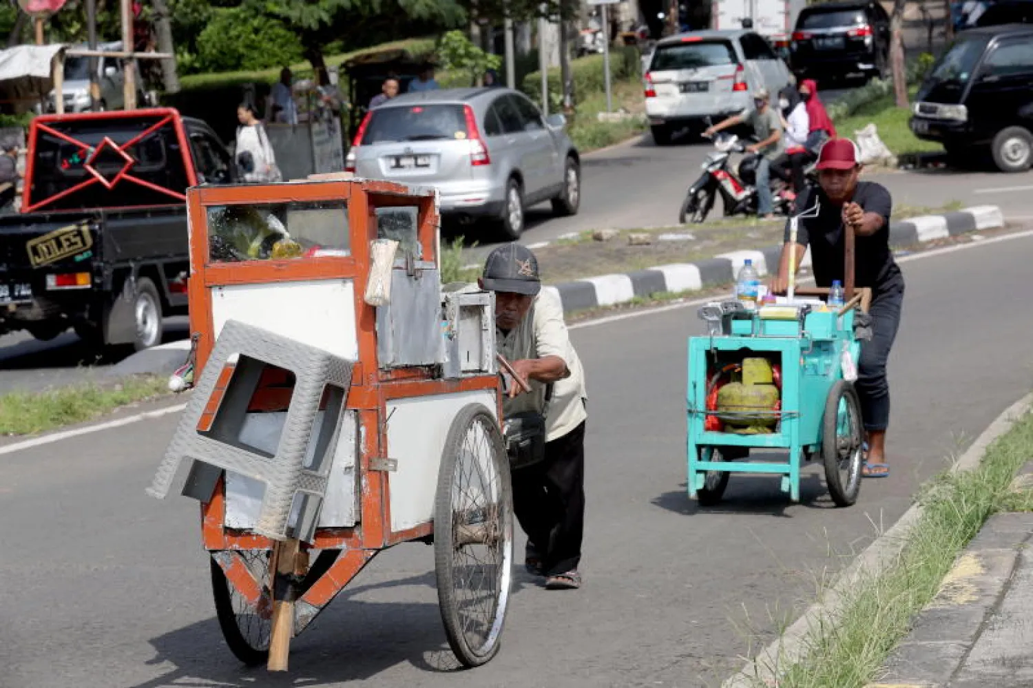 عاملان يحاولان بيع الحلوى في أحد شوارع العاصمة الإندونيسية جاكرتا (إ.ب.أ)