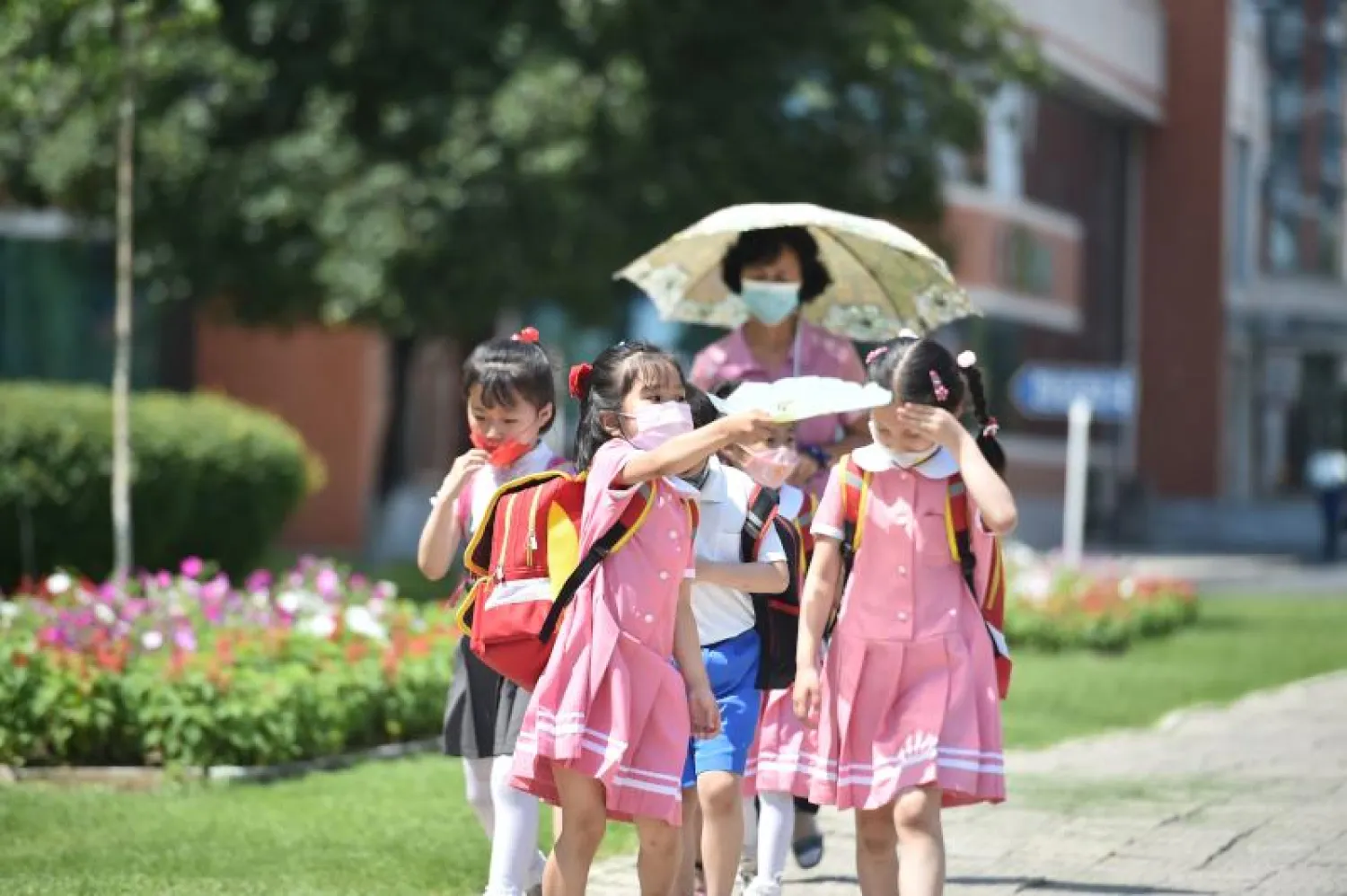 أطفال يسيرون في أحد شوارع بيونغ يانغ وسط درجات حرارة مرتفعة (أ.ف.ب)