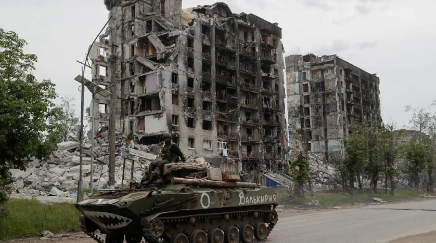 Service members of pro-Russian troops drive an armored vehicle along a street past a destroyed residential building during Ukraine-Russia conflict in the town of Popasna in the Luhansk Region, Ukraine May 26, 2022. The writing on the vehicle reads: "Valkyrie". (Reuters)
