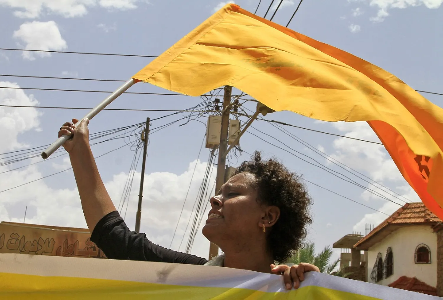 A Sudanese woman raises a flag during a rally in the capital Khartoum, as a group of women join the ongoing protests against military rule, on July 6, 2022. (AFP)