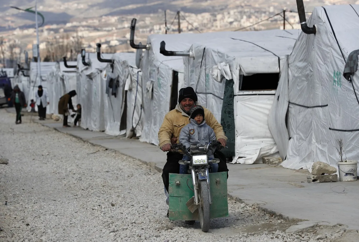 A Syrian displaced man and his son ride a motorcycle, as they drive between the tents at a refugee camp, in Bar Elias, in eastern Lebanon's Bekaa valley, March 5, 2021. (AP)