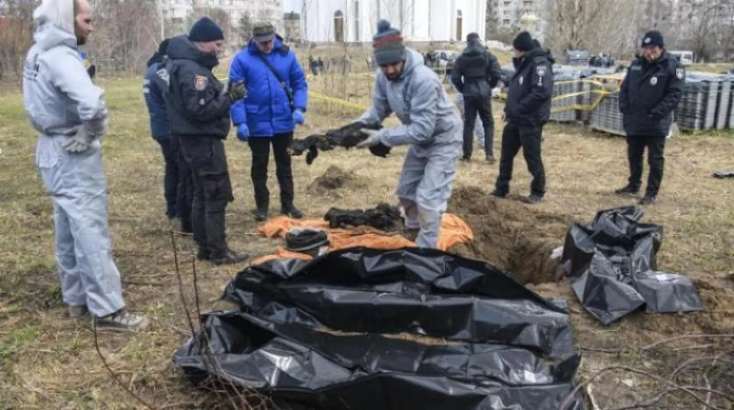Fransız müfettişler Buça kasabasında bir toplu mezarın yanında duruyor (AFP)